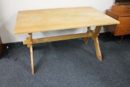 A blond oak dining table on X-framed base