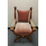 A heavily carved walnut X-framed armchair in pink dralon