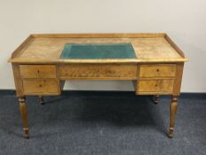 A continental satinwood five drawer desk with inset panel and gallery