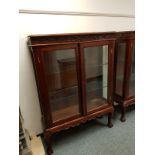 A reproduction mahogany glazed double door cabinet on claw and ball feet,