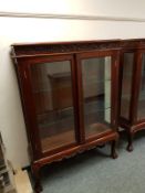 A reproduction mahogany glazed double door cabinet on claw and ball feet,