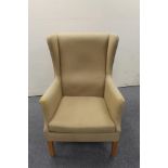 A mid 20th century wingback armchair in sand colour fabric