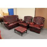 A four piece red button leather Chesterfield lounge suite comprising three seater settee,