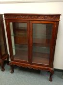 A reproduction mahogany glazed double door cabinet on claw and ball feet,