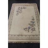 A cream fringed floral embossed Indian carpet