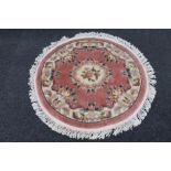 A circular fringed Chinese rug on pink ground