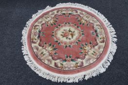 A circular fringed Chinese rug on pink ground