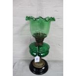 A Victorian brass oil lamp on wooden base with green glass reservoir and shade
