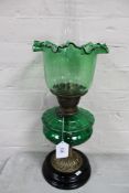 A Victorian brass oil lamp on wooden base with green glass reservoir and shade