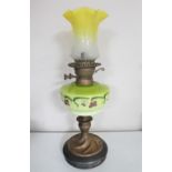 A Victorian oil lamp with hand painted glass reservoir and two tone glass shade