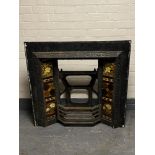 An antique cast iron tiled fire place and bucket of fireplace tiles