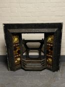 An antique cast iron tiled fire place and bucket of fireplace tiles