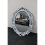 An ornate silvered oval framed mirror