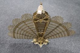 A decorative brass peacock fire screen