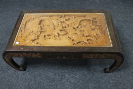 A carved hardwood Chinese coffee table with frieze panel top depicting a battle scene