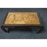 A carved hardwood Chinese coffee table with frieze panel top depicting a battle scene