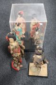 A perspex display case together with six Geisha figures