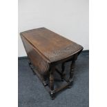 An antique carved oak gate leg table