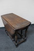 An antique carved oak gate leg table