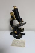 An early 20th century microscope, black metal and brass, stamped "BACT. MED. SCH.