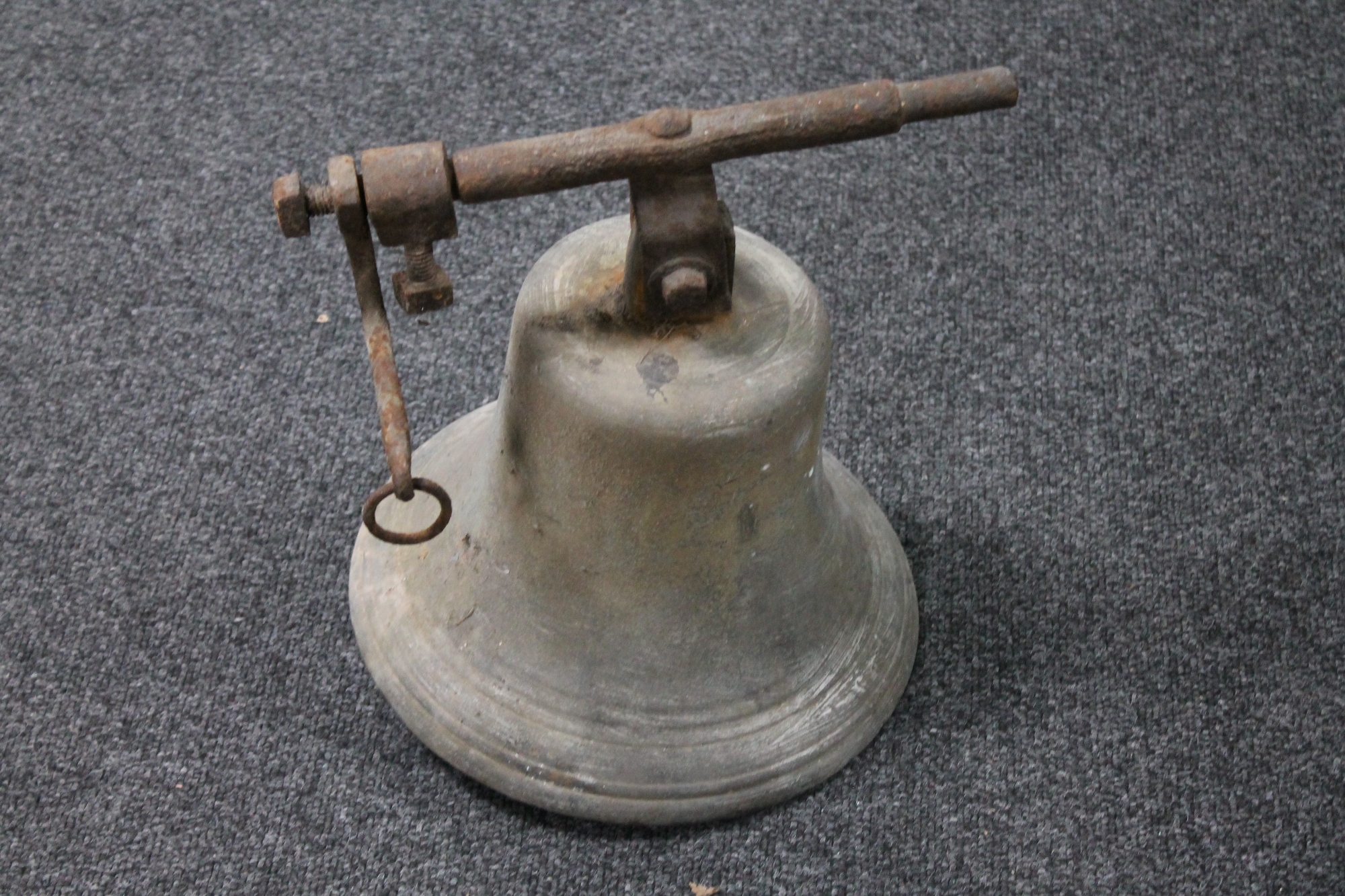 An antique cast metal church bell with bracket