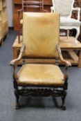 An antique continental carved oak armchair upholstered in tan leather