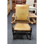 An antique continental carved oak armchair upholstered in tan leather