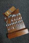 An Edwardian wooden spoon rack fitted with a glove box containing pewter spoons, tie press.