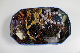 A tin of costume jewellery, necklaces,