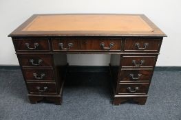 A mahogany Regency style pedestal writing desk with nine drawers and tooled leather top