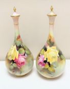 A pair of Royal Worcester hand painted bulbous lidded vases with gilt finials,