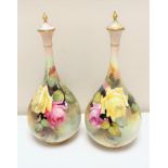 A pair of Royal Worcester hand painted bulbous lidded vases with gilt finials,