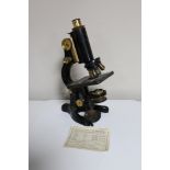 An early 20th century microscope, black metal and brass, stamped "BACT. MED. SCH.