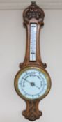 An early 20th century carved oak cased barometer with enamel dial