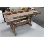 An early 20th century wooden work bench with two wooden vices
