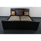 A 6' brown leather bed frame together with three large brown leather scatter cushions