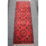 A fringed Afghan rug on red ground