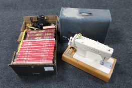 A cased Singer electric sewing machine (no foot pedal) together with a box containing three volumes