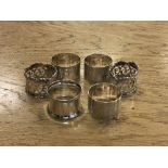 Two pairs of ornate silver napkin rings and two other singles.