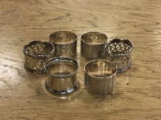 Two pairs of ornate silver napkin rings and two other singles.