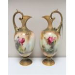 A pair of Royal Worcester gilded ewers hand-painted by R.H.