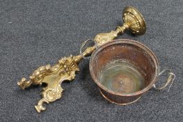 An antique twin-handled brass pan and an ornate brass candlestick