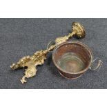 An antique twin-handled brass pan and an ornate brass candlestick