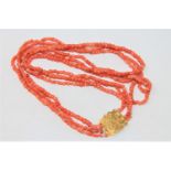 An antique triple strand coral necklace with high carat gold clasp