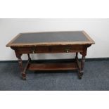 An oak Arts and Crafts leather topped writing table with two drawers and undershelf