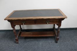 An oak Arts and Crafts leather topped writing table with two drawers and undershelf