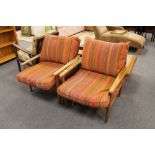 A pair of mid 20th century teak framed armchairs in stripped fabric and loose cushions