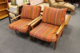 A pair of mid 20th century teak framed armchairs in stripped fabric and loose cushions