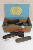 A box of antique collectables to include cased spectacles, pipes, tape measures, OXO tin,