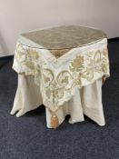 A circular metal based occasional table with cream and gilt table cover